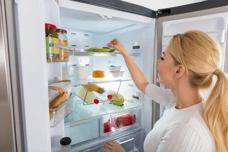 אישה פותחת מקרר ולוקחת צלחת עם אוכל