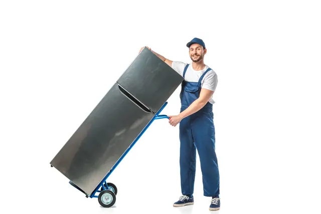 מוביל בסרבל כחול מטה מקרר נירוסטה על עגלת הובלה כחולה